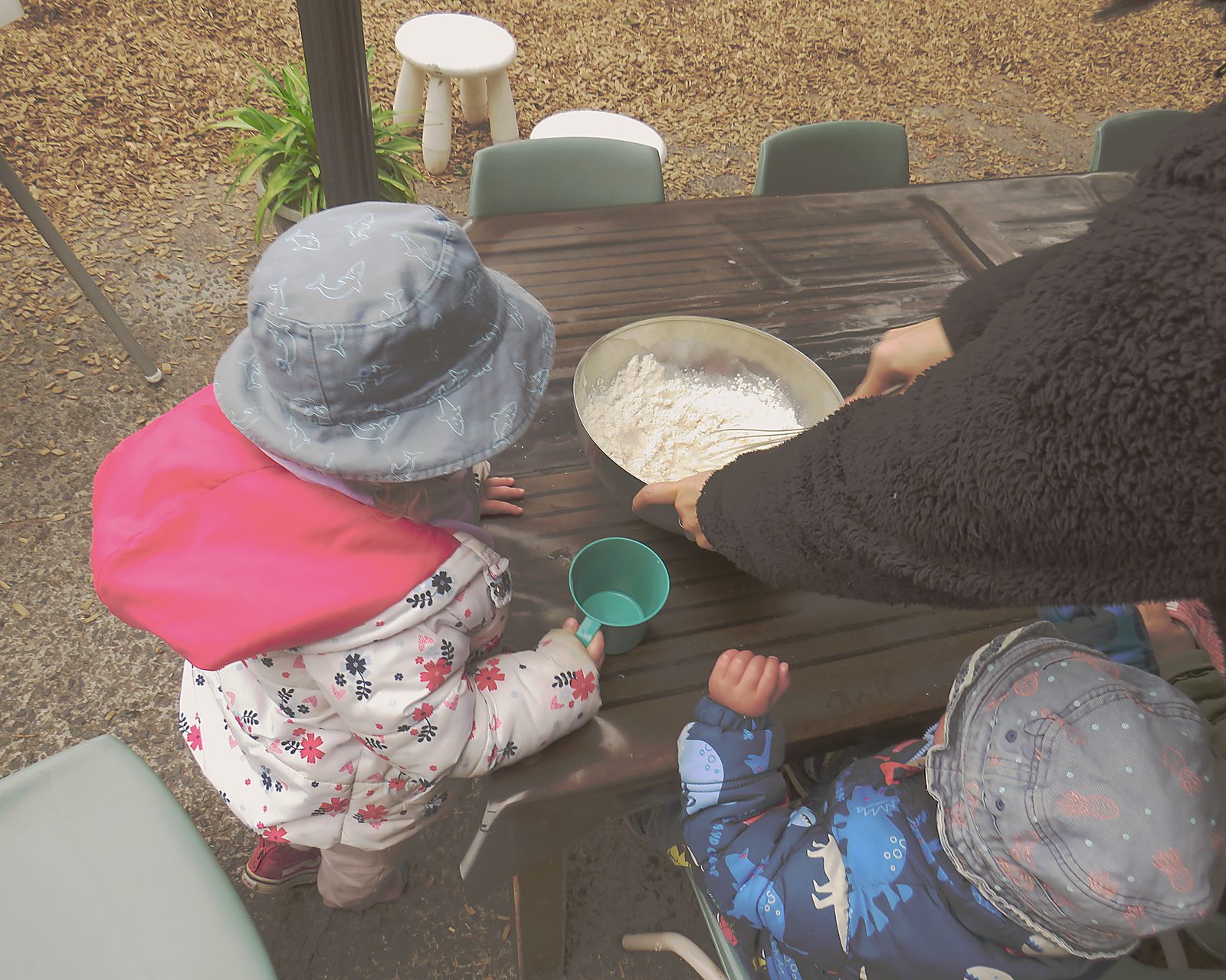A child's hands measuring ingredients alongside an educator. Food made here, every day